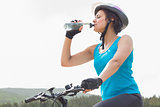 Athletic woman on mountain bike drinking water