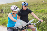 Couple on mountain bikes reading map