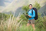 Attractive female hiker with backpack holding a map