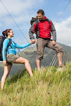 Handsome hiker helping his girlfriend uphill