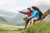 Couple taking a break after hiking uphill and holding map