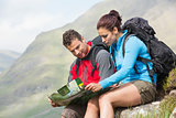 Couple resting after hiking uphill and reading map