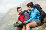 Couple resting after hiking uphill and holding map