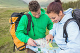 Couple sitting after hiking uphill and consulting map