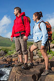 Couple standing at edge of river on a hike holding hands