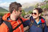 Couple wearing rain jackets and sunglasses smiling at each other
