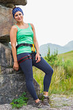 Attractive female rock climber leaning on rock face smiling at camera