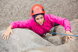 Smiling girl climbing up rock face