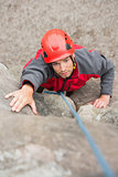 Focused man climbing rock face