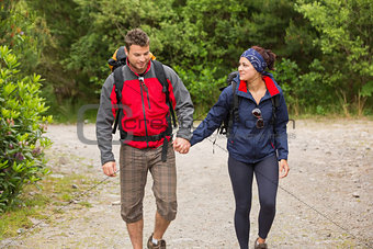 Smiling couple going on a hike together holding hands