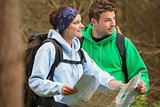 Smiling couple standing in a forest holding map