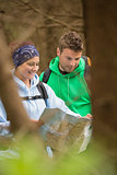 Happy couple standing in a forest reading map