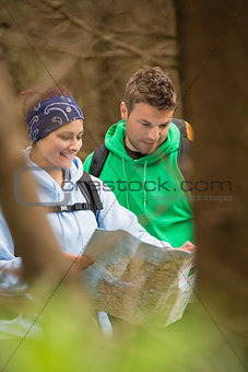 Happy couple standing in a forest reading map
