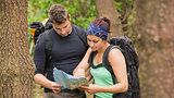 Fit couple reading map in a forest