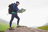 Woman standing on a rock reading map
