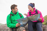Couple using map and compass sitting on a rock