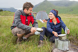 Couple cooking outside on camping trip and smiling