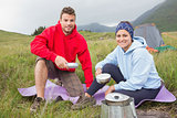 Couple cooking outside on camping trip smiling at camera
