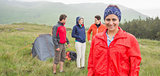 Brunette smiling at camera with friends behind her on camping trip