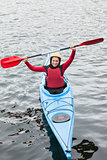 Happy woman in a kayak cheering at the camera
