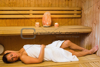 Happy brunette woman lying in a sauna