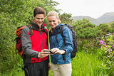 Happy couple on a hike looking at photo on smartphone
