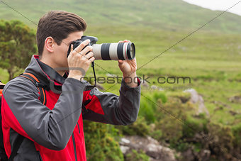 Handsome man on a hike taking a photograph