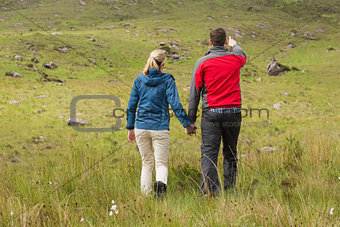 Couple holding hands on walk with man pointing