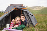 Happy couple lying in their tent and looking at camera