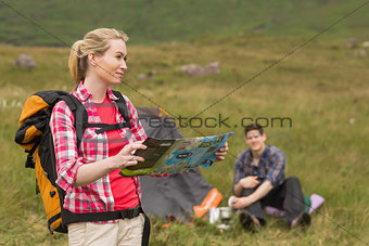 Smiling woman carrying backpack and holding map