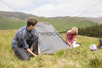 Happy couple pitching their tent