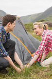 Smiling couple pitching their tent together