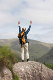 Woman standing on rock cheering after a hike