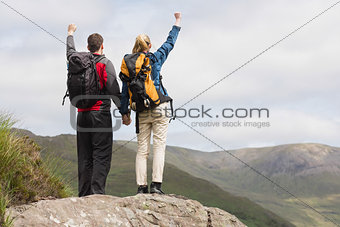 Excited couple reaching the top of their hike and cheering