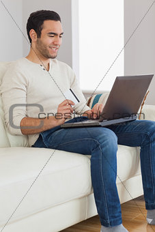 Smiling handsome man using his credit card to buy online