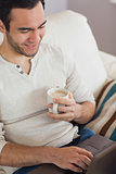 Calm attractive man drinking coffee while using his laptop