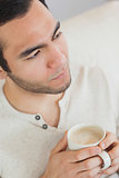 Thoughtful handsome man holding cup of coffee