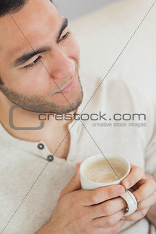 Smiling thoughtful man holding cup of coffee
