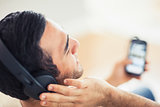 Close up on handsome man listening to music on his smartphone