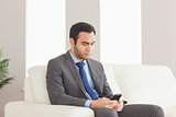 Serious businessman sitting on cosy sofa