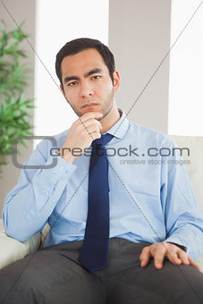 Young classy businessman thinking on cosy sofa