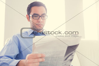 Unsmiling man reading a newspaper