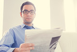 Frowning man looking at camera and holding a newspaper
