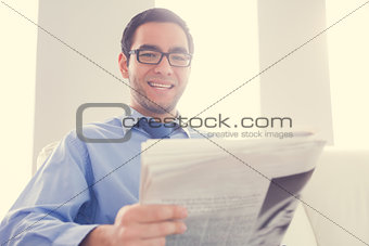 Happy man looking at camera and holding a newspaper