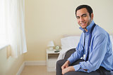 Pleased man looking at camera and relaxing sitting on his bed