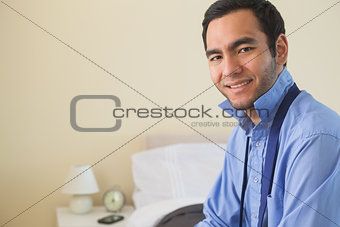 Content man looking at camera and relaxing sitting on his bed