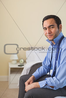 Satisfied man looking at camera and relaxing sitting on his bed