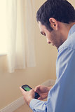 Close up of a man using a mobile phone sitting on a bed