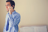 Bored man calling someone with a mobile phone and looking away