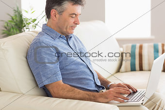 Thinking man sitting on sofa using laptop